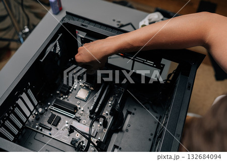 High-angle view of technician applying processor into desktop motherboard during computer hardware upgrade or repair process at dark workshop. Concept of desktop PC maintenance and service. 132684094