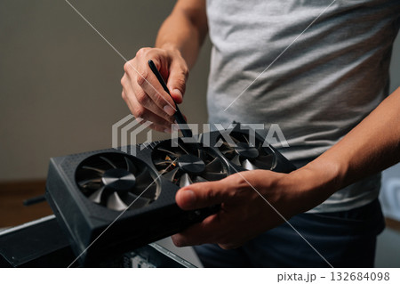 Close-up cropped shot of unrecognizable cleaning graphics card with brush, performing essential maintenance on computer hardware to ensure optimal performance. Concept of computer hardware service Close-up cropped shot of unrecognizable cleaning graphics card with brush, performing essential maintenance on computer hardware to ensure optimal performance. Concept of computer hardware service 132684098