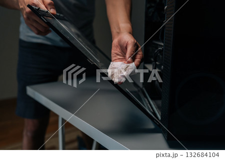 Cropped shot of computer technician wiping glass panel, clearing dust buildup and improving internal airflow for enhanced electronic system performance and longevity. Concept of service, cleaning PC. Cropped shot of computer technician wiping glass panel, clearing dust buildup and improving internal airflow for enhanced electronic system performance and longevity. Concept of service, cleaning PC. 132684104