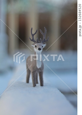 A charming felt deer figurine stands gracefully in soft white snow, evoking a cozy winter atmosphere. Concept of winter decorations, childlike wonder, and holiday cheer. A charming felt deer figurine stands gracefully in soft white snow, evoking a cozy winter atmosphere. Concept of winter decorations, childlike wonder, and holiday cheer. 132684520