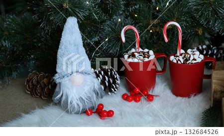 Holiday cheerful gnome with grey hat atop white sleigh, joined by two red mugs with hot chocolate, surrounded by pinecones, glowing golden bells, lush green branches, bringing festive energy Holiday cheerful gnome with grey hat atop white sleigh, joined by two red mugs with hot chocolate, surrounded by pinecones, glowing golden bells, lush green branches, bringing festive energy 132684526