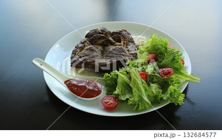Roasted beef with greens, red sauce and pita on white plate  132684577