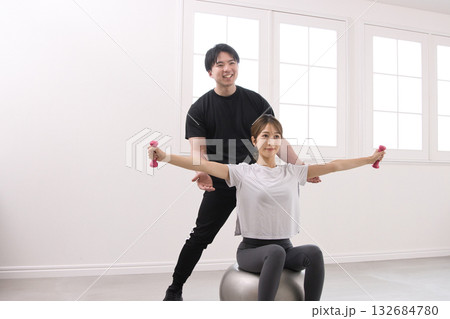 パーソナルトレーナーにトレーニングを受ける若い女性 パーソナルトレーナーにトレーニングを受ける若い女性 132684780