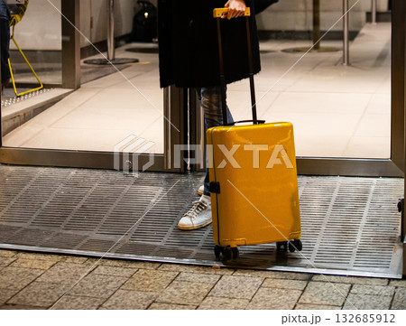 A traveler with a bright suitcase at a doorway. A traveler with a bright suitcase at a doorway. 132685912