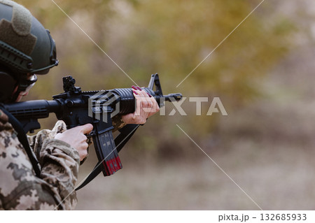 A woman in camouflage aims a rifle. A woman in camouflage aims a rifle. 132685933