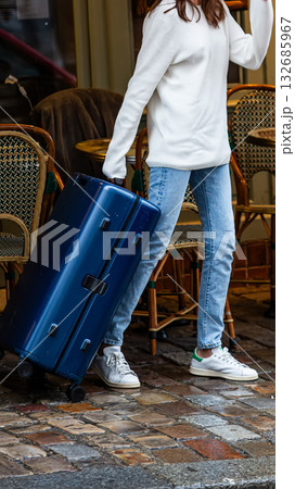 A modern traveler with a suitcase on a cobblestone street. 132685967