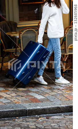 A modern traveler with a suitcase on a cobblestone street. 132685968