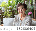 植物に囲まれたテラスの椅子に座って微笑むシニア女性 132686405