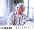 大きな窓から光の差し込むリビングで窓の外を見つめる笑顔のシニア女性 132686407