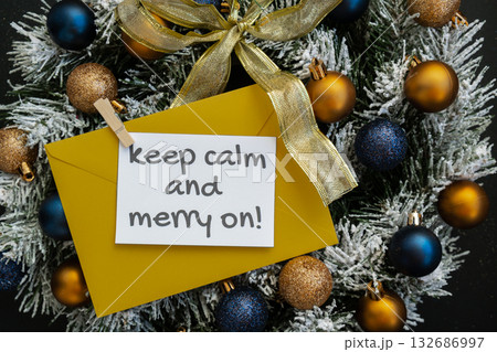 KEEP CALM ANA MERRY ON text on postcard with yellow envelope on handmade Christmas wreath. Zero waste eco-friendly Christmas. Sustainable greeting card 132686997