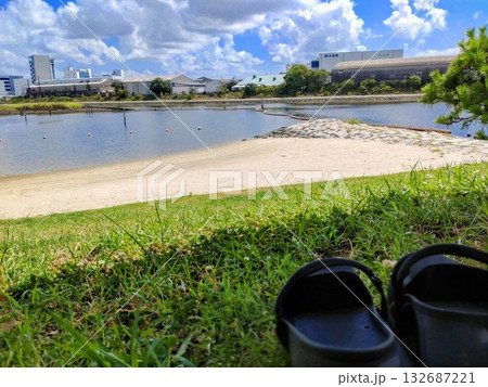 芝生と砂浜のある公園に置かれた黒い靴 132687221