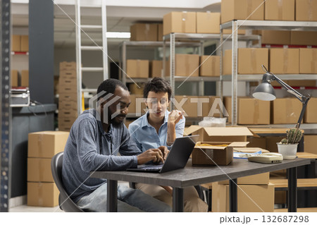 Multiethnic staff managing inventory and order systems in distribution hub, reflecting the structured business processes of a small business organized logistics center. Storehouse cargo. 132687298