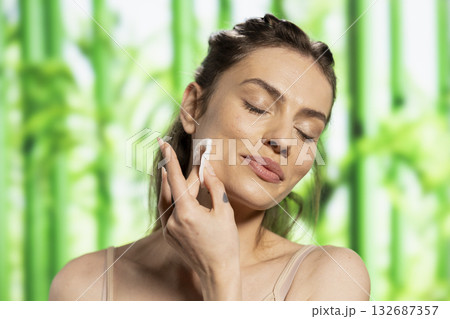 Portrait of a beautiful person removing makeup with cotton pads, embracing her glowing skin and nourishment cleansing routine. Skincare moment reflects body positivity with a natural look. Portrait of a beautiful person removing makeup with cotton pads, embracing her glowing skin and nourishment cleansing routine. Skincare moment reflects body positivity with a natural look. 132687357