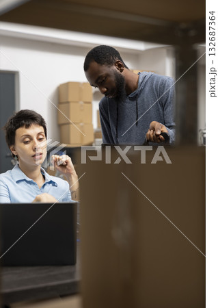 Diverse team overseeing orders and merchandise for local business operations, working in a shipping area industrial depot. Staff utilizing modern technology logistics for e commerce. 132687364