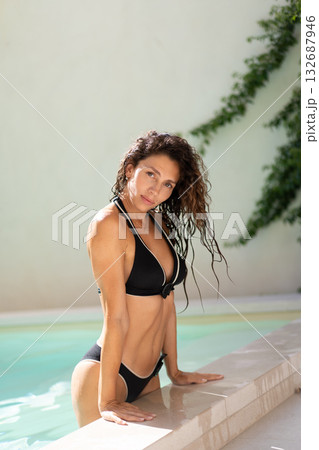 Confident woman in black bikini leaning on 132687946