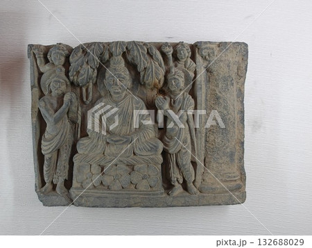 ガンダーラ美術にある仏教彫刻のひとつで人々から礼賛合掌される仏陀の姿を表したレリーフ ガンダーラ美術にある仏教彫刻のひとつで人々から礼賛合掌される仏陀の姿を表したレリーフ 132688029