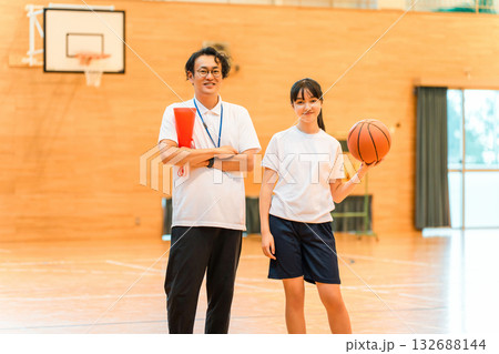 体育館にいる部活の顧問の男性教師とバスケットボールを持つ女子生徒 体育館にいる部活の顧問の男性教師とバスケットボールを持つ女子生徒 132688144