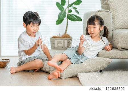 リビングのソファーでおやつを食べる仲良しの兄妹 リビングのソファーでおやつを食べる仲良しの兄妹 132688891