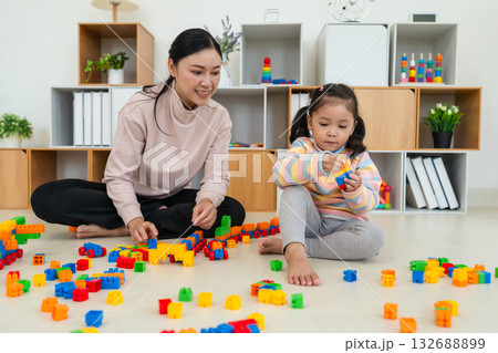 happy toddler girl and mother playing building blocks or plastic bricks toy at home 132688899
