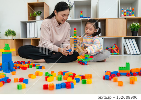 happy toddler girl and mother playing building blocks or plastic bricks toy at home happy toddler girl and mother playing building blocks or plastic bricks toy at home 132688900