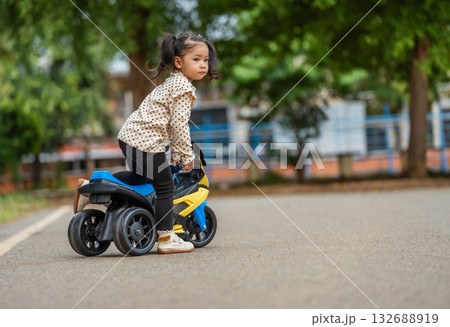 toddler girl riding an electric motorcycle toy in park toddler girl riding an electric motorcycle toy in park 132688919