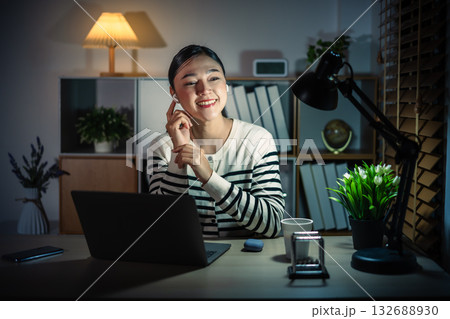 happy young woman using wireless earbuds to listening music and laptop at night 132688930