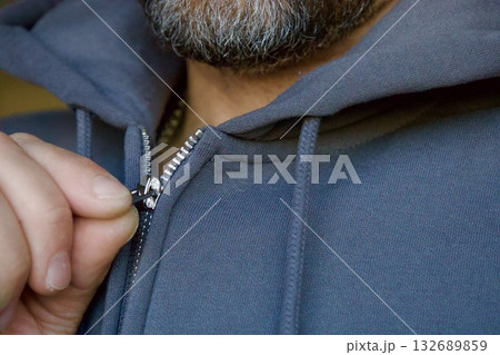 Bearded man zipping grey hoodie close up 132689859
