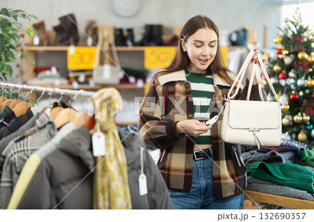 Woman client looks at products in store, choose closely ladys bag Woman client looks at products in store, choose closely ladys bag 132690357