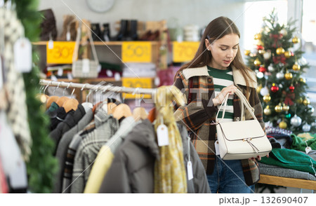 adult woman chooses fashionable handbags in a store against the background of a Christmas tree 132690407