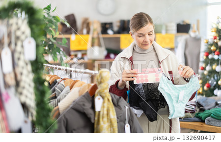 Woman client looks at products in store, choose closely panties 132690417