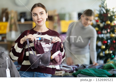 Uncertain young woman choosing bra in clothing store Uncertain young woman choosing bra in clothing store 132690521