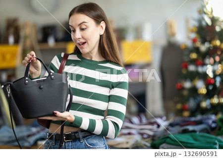 Positive young woman choosing handbag in clothing store 132690591
