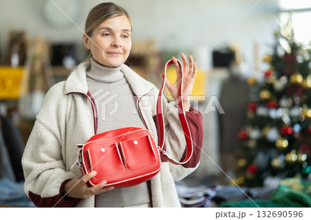 Positive young woman choosing handbag in clothing store 132690596