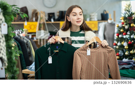 Young woman chooses warm dress in clothing store 132690636