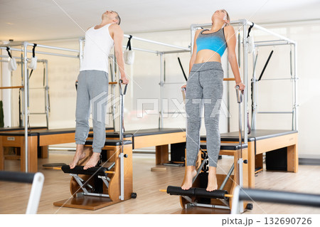 Sporty couple practicing Pilates on wunda chairs in fitness studio 132690726