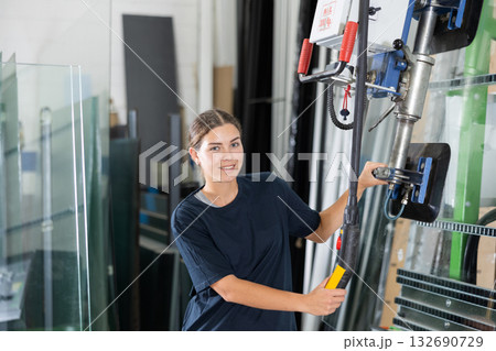 Female technician operating vacuum glass lifting machine in workshop 132690729
