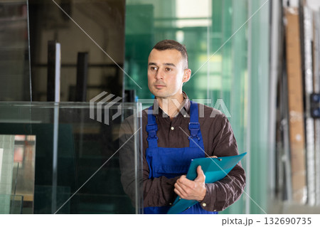 Worker inspecting glass panels and recording check results Worker inspecting glass panels and recording check results 132690735