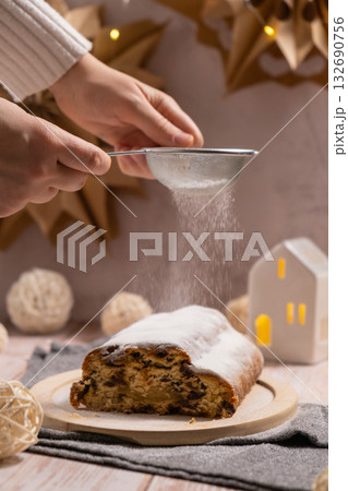 Homemade Christmas traditional cake pie with falling sugar powder with marzipan nuts and dried fruits pastry dessert stollen. Winter holidays season atmosphere. Delicious tasty composition home table 132690756