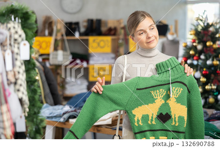 Uncertain young woman choosing sweater in clothing store 132690788