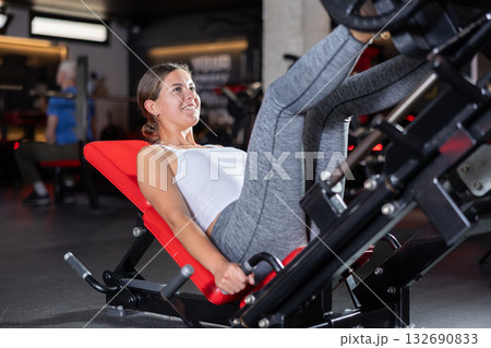 Sporty girl pulls his legs to his chest on special simulator 132690833