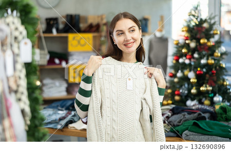 Young woman chooses sweater in clothing store Young woman chooses sweater in clothing store 132690896