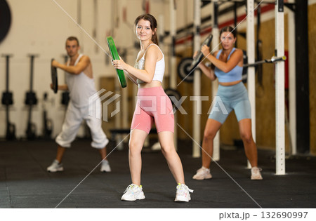Closeup of athletic sports girl standing with plate of barbell in hands in fitness studio Closeup of athletic sports girl standing with plate of barbell in hands in fitness studio 132690997