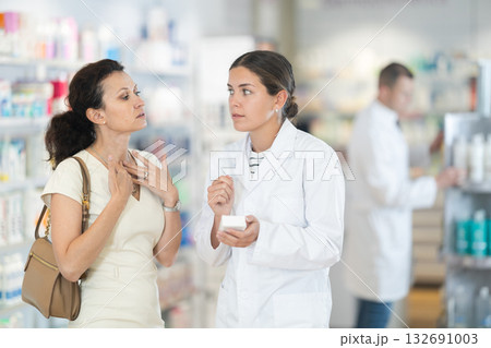 Pharmacist advises medicine for sore throat to woman Pharmacist advises medicine for sore throat to woman 132691003