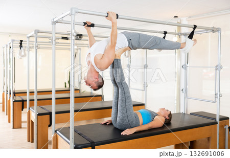 Couple engaging in advanced Pilates exercises on trapeze table 132691006