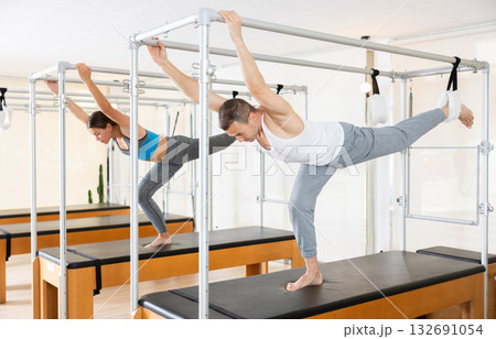 Girl and man is stretching body with pilates machine 132691054