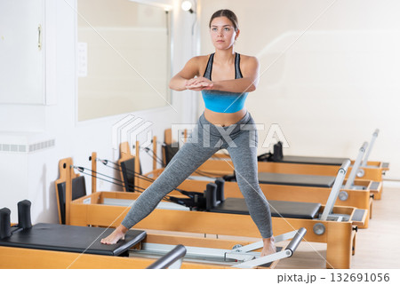Girl practicing exercises on Pilates reformer during rehabilitation session 132691056