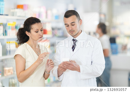 Man pharmacist helps woman buyer to decide on choice an medicine 132691057