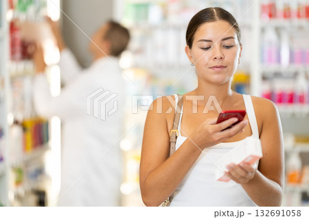 In pharmacy girl customer scans QR code on label box, photographs packaging. 132691058