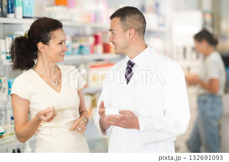 Male pharmacist consulting woman customer about medicament in box Male pharmacist consulting woman customer about medicament in box 132691093