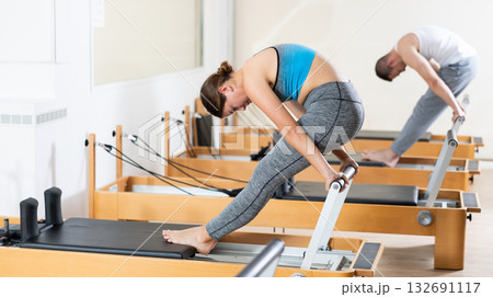 Girl doing stretching exercises on reformer in pilates studio Girl doing stretching exercises on reformer in pilates studio 132691117
